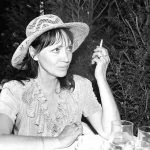 Une femme au chapeau de paille fumant une cigarette.