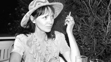 Une femme au chapeau de paille fumant une cigarette.
