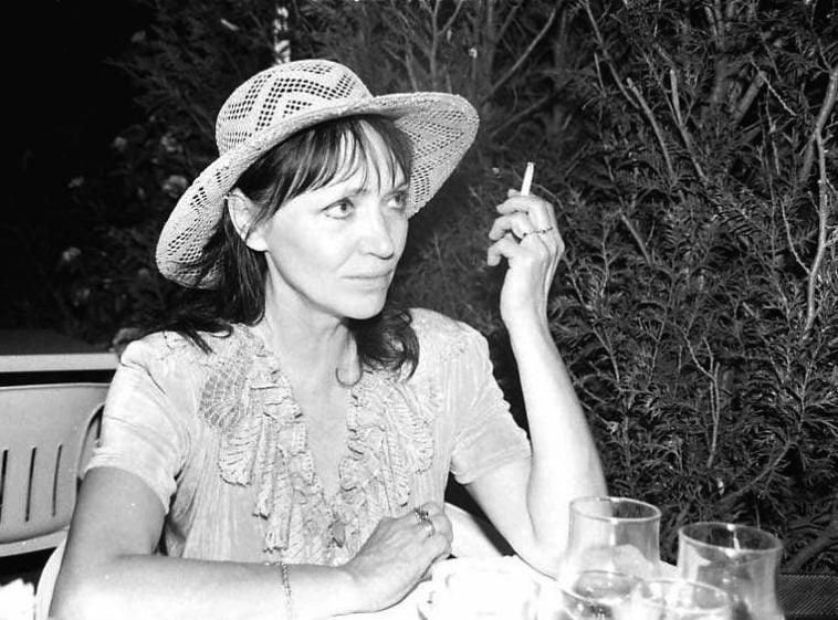 Une femme au chapeau de paille fumant une cigarette.
