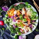 Un bol de salade asiatique avec des radis et des baguettes.