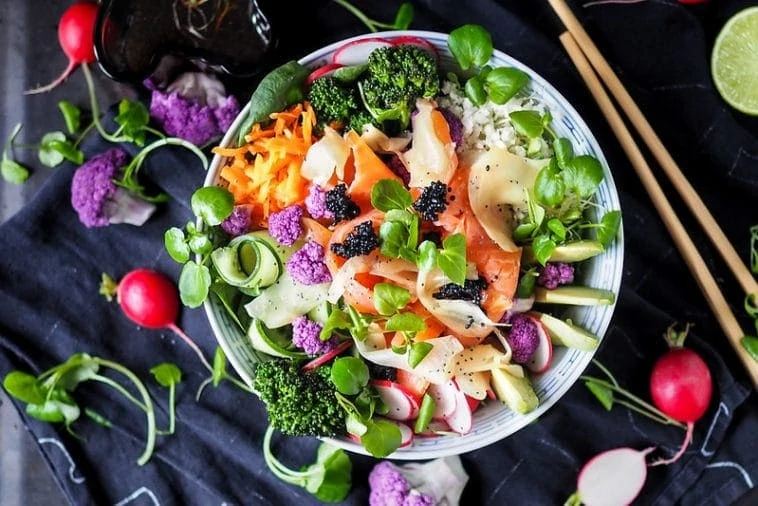 Un bol de salade asiatique avec des radis et des baguettes.