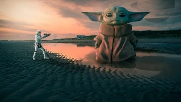 Un bébé Yoda se tient sur la plage à côté d’une planète.