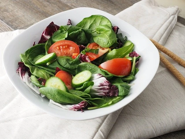 Un bol de salade d'épinards avec tomates et concombres.