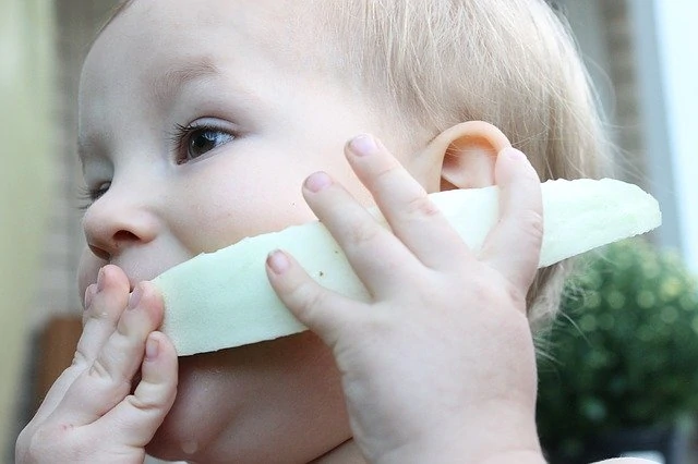 Un bébé pratique La DME en tenant un morceau de melon dans sa bouche.
