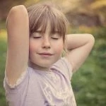 Une petite fille pose les mains sur la tête.