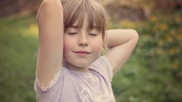 Une petite fille pose les mains sur la tête.