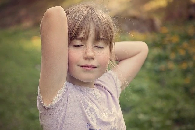 Une petite fille pose les mains sur la tête.