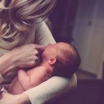 Une femme tient un bébé dans ses bras.