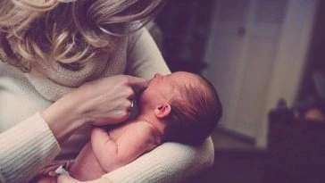 Une femme tient un bébé dans ses bras.