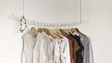 Vêtements suspendus à un portant dans une pièce blanche.