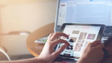 Une personne utilisant un iPad sur un bureau avec un ordinateur portable.