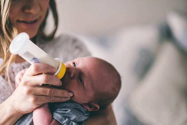 Une femme nourrit un bébé avec un biberon.