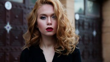 Une jeune femme aux longs cheveux bouclés et au rouge à lèvres.