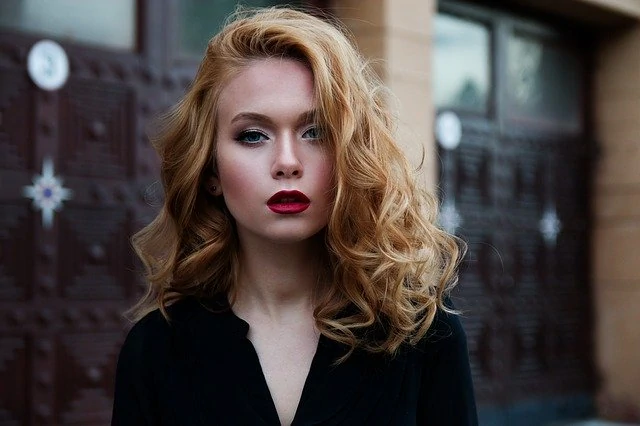 Une jeune femme aux longs cheveux bouclés et au rouge à lèvres.
