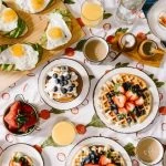 Petit-déjeuner avec gaufres, œufs et fruits sur une nappe.