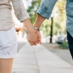 Un couple se tenant la main en marchant dans la rue.