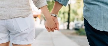 Un couple se tenant la main en marchant dans la rue.