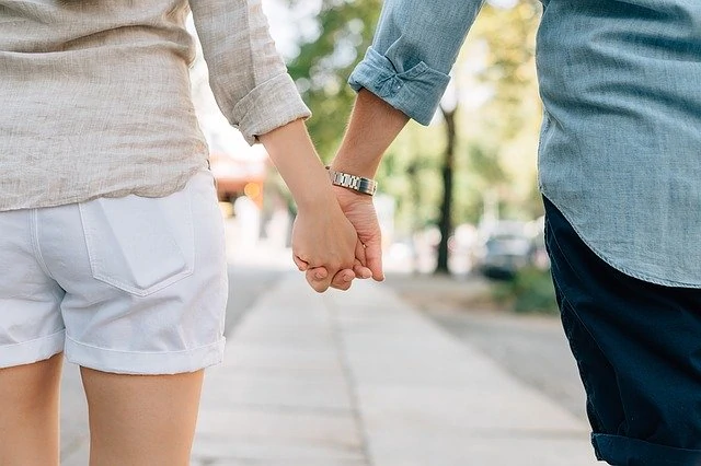 Un couple se tenant la main en marchant dans la rue.