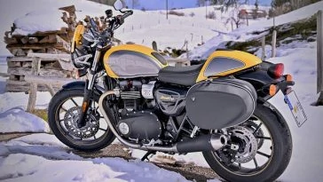 Une moto jaune et noire garée dans la neige.