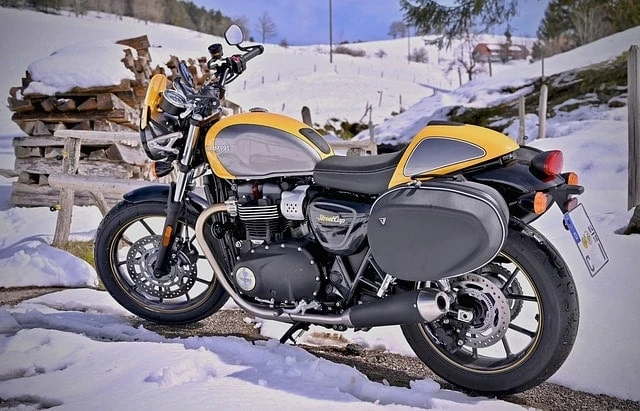 Une moto jaune et noire garée dans la neige.