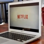 Un ordinateur portable portant le logo Netflix est posé sur une table.