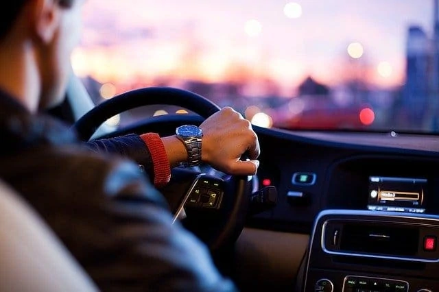 Un homme conduisant une voiture avec les mains sur le volant.