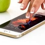 Le doigt d'une femme touche une pomme sur un iPhone.