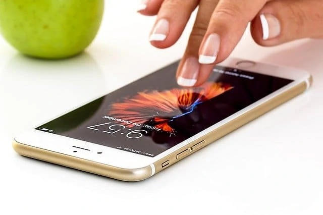 Le doigt d'une femme touche une pomme sur un iPhone.