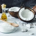 Huile de coco, sucre et cuillère en bois sur une table en bois.