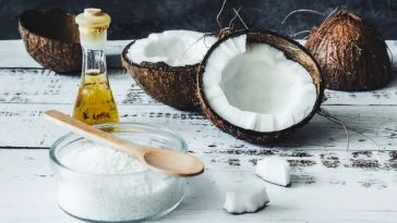 Huile de coco, sucre et cuillère en bois sur une table en bois.