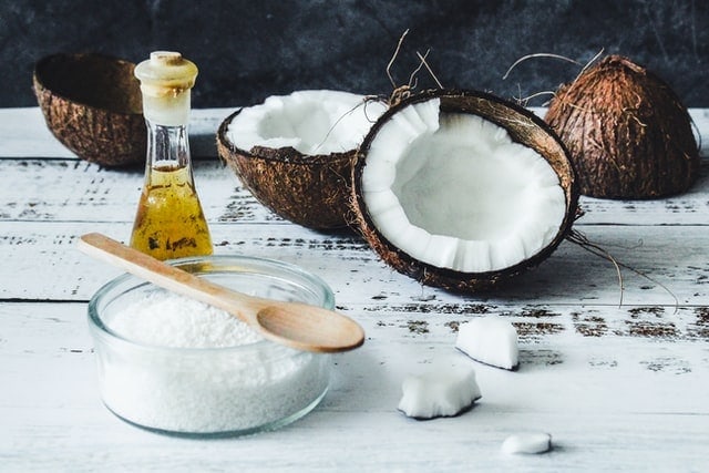 Huile de coco, sucre et cuillère en bois sur une table en bois.