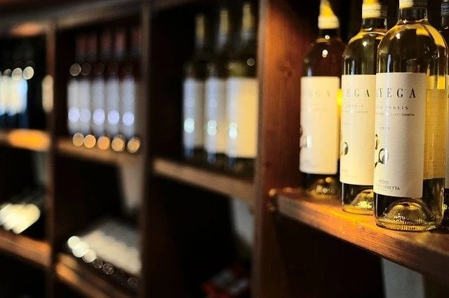 De nombreuses bouteilles de vin sont alignées sur une étagère en bois.