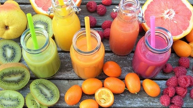 Une variété de jus de fruits sont disposés sur une table en bois.