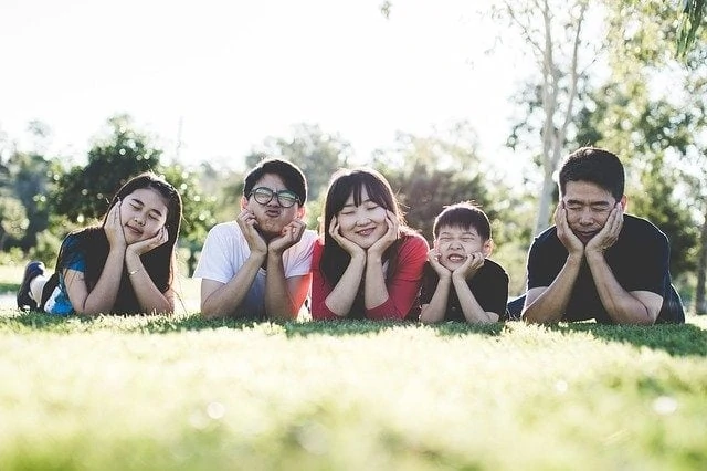 Une famille allongée sur l’herbe dans un parc.