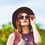 Une femme bohème avec un chapeau et des lunettes de soleil indispensables.