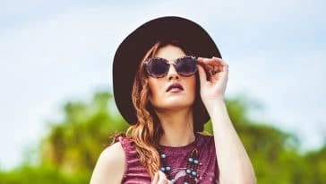 Une femme bohème avec un chapeau et des lunettes de soleil indispensables.