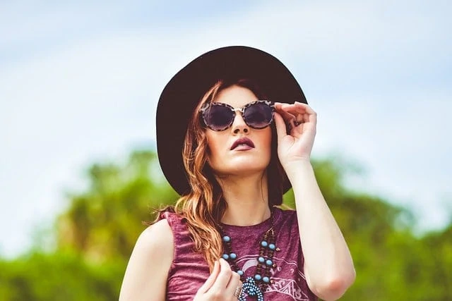 Une femme bohème avec un chapeau et des lunettes de soleil indispensables.