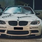 Une BMW M3 blanche garée devant un immeuble.