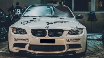 Une BMW M3 blanche garée devant un immeuble.