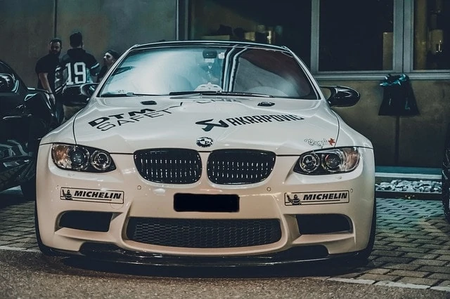 Une BMW M3 blanche garée devant un immeuble.