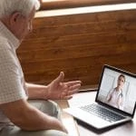 Un homme âgé utilise la téléassistance pour parler à un médecin sur un ordinateur portable.