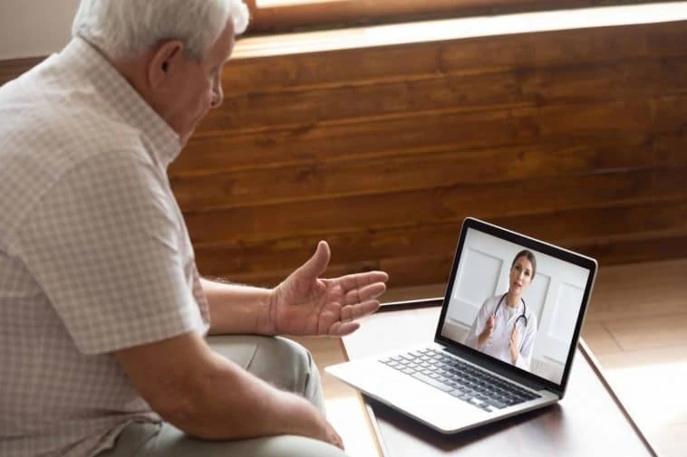 Un homme âgé utilise la téléassistance pour parler à un médecin sur un ordinateur portable.