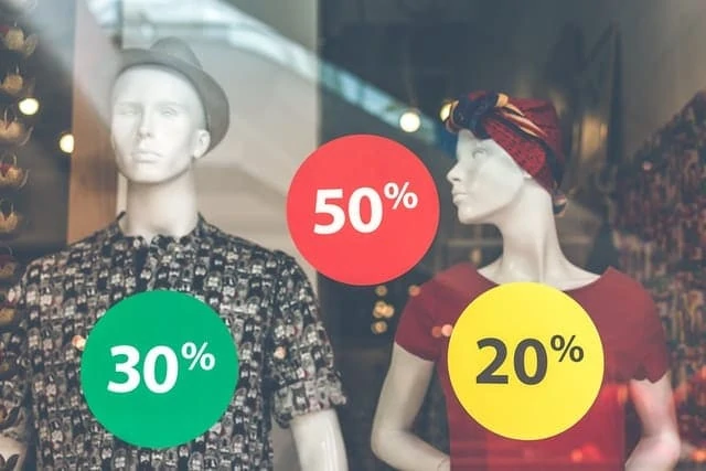 Mannequins devant une fenêtre avec une pancarte de vente.