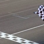 Un homme agitant un drapeau à damier sur une piste de course.