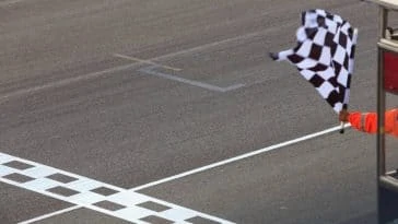 Un homme agitant un drapeau à damier sur une piste de course.