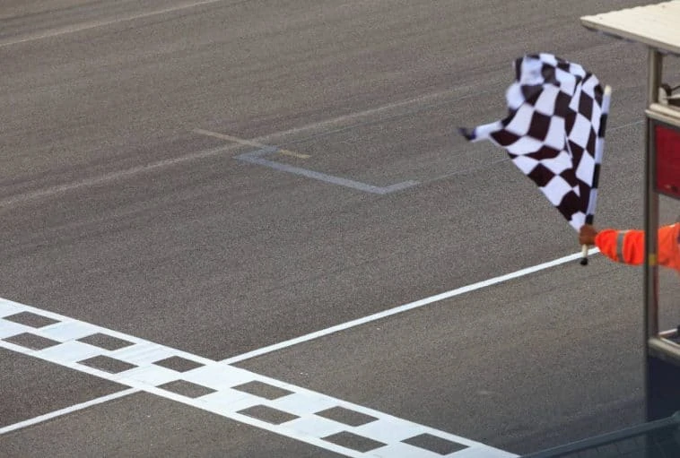 Un homme agitant un drapeau à damier sur une piste de course.