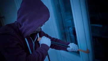 Un cambrioleur en sweat à capuche ouvre une porte avec un couteau à Paris.