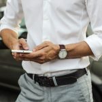 Un homme en chemise blanche utilise son téléphone portable.