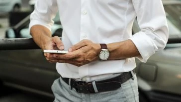 Un homme en chemise blanche utilise son téléphone portable.