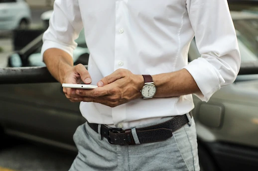 Un homme en chemise blanche utilise son téléphone portable.